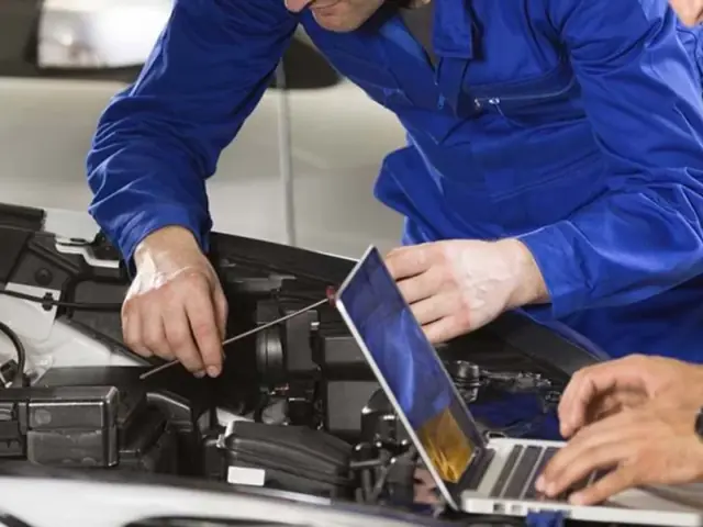 Mecânico fazendo diagnóstico eletrônico com notebook no motor